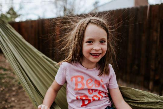 Young girl with static hair sitting on hammock