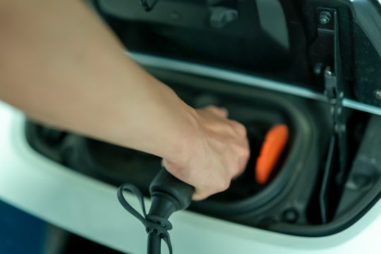 young man plugging in his electric vehicle