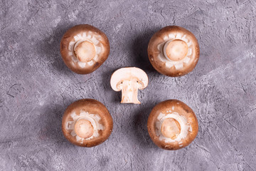 Whole and cut brown champignon on gray background