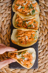 Mexican tacos on a row and a hand holding one