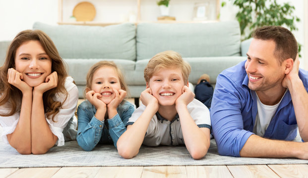 Happy Family Of Four Lying On Floor Posing At Home