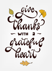 Creative hand lettering quote 'Give thanks with a grateful heart' decorated with leaves on light grey background. Poster, card, print design.