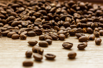 Roasted arabica coffee beans, in bulk on a wooden table.