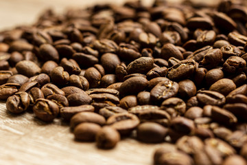 Roasted arabica coffee beans, in bulk on a wooden table.