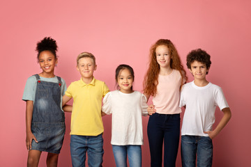 Back to school concept. Happy diverse boys and girls posing over pink background