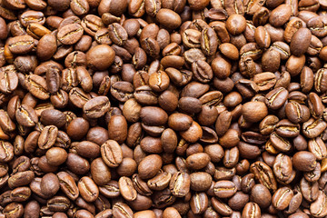 Roasted arabica coffee beans, in bulk on a wooden table.