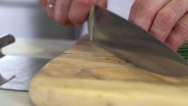 Dropping chives on chopping board before finely chopping, close up