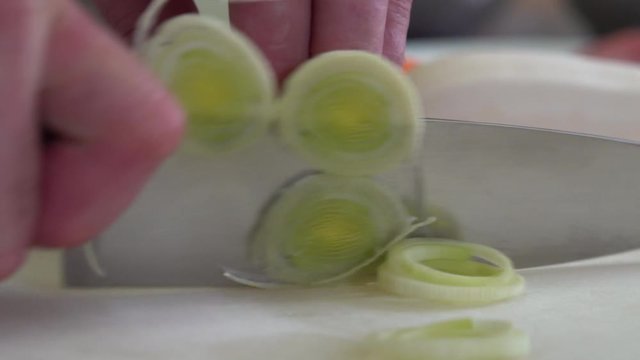 Chef finely chopping leek on chopping board, close up