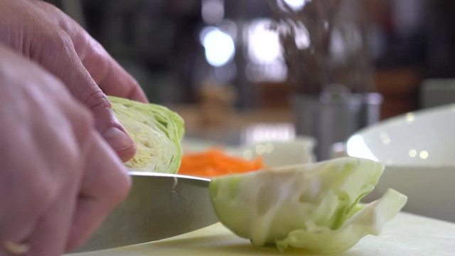 Chef finely chopping cabbage on chopping board, close up