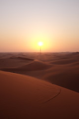 Fototapeta na wymiar Portrait of beautiful desert sunrise with power transmission tower in the Arabian Desert, Riyadh, Saudi Arabia. Hope, new beginnings, brighter tomorrow and solar energy concept.