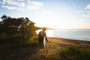 man carrying his paddle board at sunset 