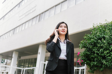 Beautiful asian business woman talking on cellphone while walking outdoor