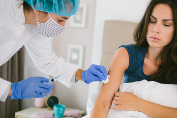 The female doctor in protective equipment a mask, gloves performs the vaccination procedure. Human vaccination process against coronavirus. Female scared getting an injection from a doctor.