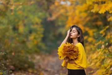 Cheerful woman portrait with autumn maple leaves in the park