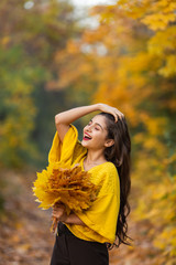 Cheerful woman portrait with autumn maple leaves in the park