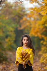 Cheerful woman portrait with autumn maple leaves in the park