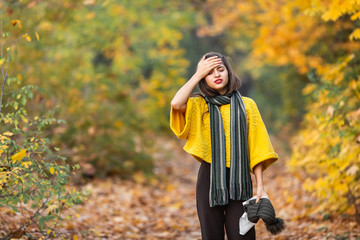 girl sneezes into a headscarf in autumn in the park. allergy or viral infection concept