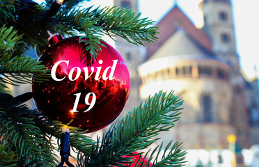 View on red glitter ball on fir tree with covid 19 text at christmas market