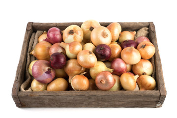 Yellow and red onions in a rustic wooden box isolated on a white background, side view. Full frame. Vegetable background. Concept of food, farm products.