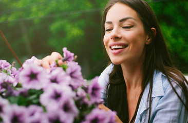 Beautiful happy young woman surrounded by flowers, enjoying in life.