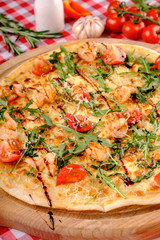 Pizza with seafood, mozzarella, mussels, octopus, squid, salmon, shrimp, cheeseand, fresh rucola and tomatoes sauce on a wooden board italian restaurant background, top view. Mediterranean food.