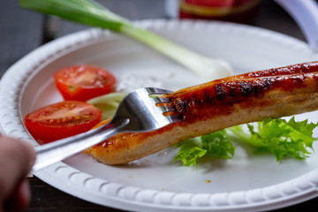 Fork impales fried juicy sausage