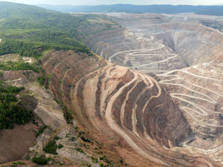 Open pit ore mining.
Photo of a pit for mining ore from the air. A string of roads in the mountains...