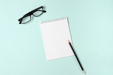 Open notebook with pencil and glasses on a blue background