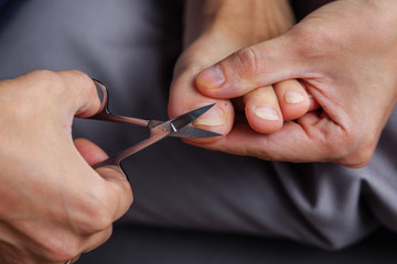 Man shearing his toenails with nail scissors