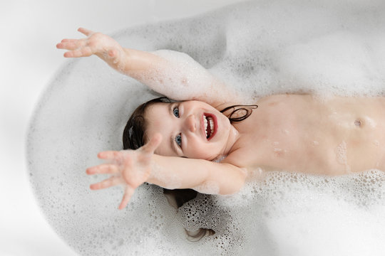 High angle portrait of happy toddler girl bathing in bathtub at home