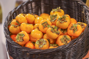 Lots of persimmon in basket at bazaar. agriculture farm full of organic vegetables. Pile of ripe persimmon in the store. (selective focus)