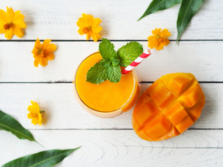 Mango juice with fresh ripe mango sliced top view on a white color wooden table for summer drinks.