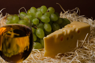 A glass of white wine with cheese and grapes. Still life