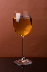Glass of white wine on a brown background. Still life