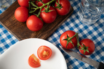 Red tomatoes on a table covered with a checkered tablecloth