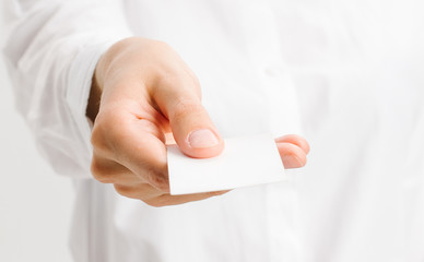  girl in a white office shirt holds out a business card. close portrait.