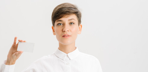  girl in a white office shirt holds out a business card. close portrait.