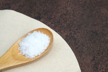 White Salt on wooden spoon rough texture background and copy space.