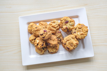 Top view homemade Freshly baked Delicious Chocolate Chip Cookies in white plate on wooden table.