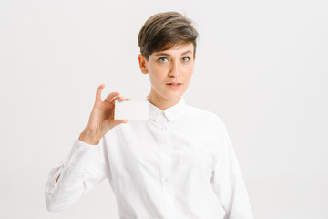  girl in a white office shirt holds out a business card. close portrait.