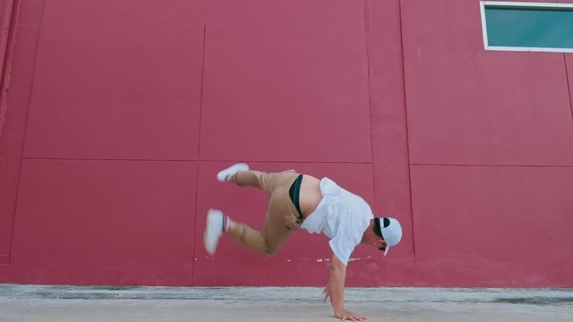 Dancing man performing various freestyle dance outdoors in street wall having fun. Modern lifestyle, happiness concept. breakdancing, hiphop dancing, street dancing.