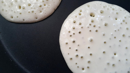 Delicious thin pancakes on a non-stick pan. Top view. Flat lay. Cooking process. Pancakes recipe.	