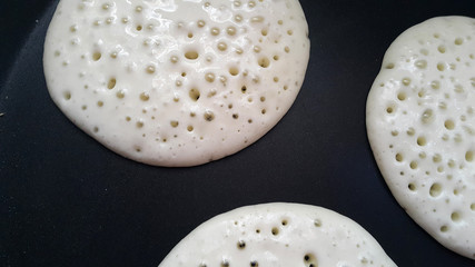 Delicious thin pancakes on a non-stick pan. Top view. Flat lay. Cooking process. Pancakes recipe.	