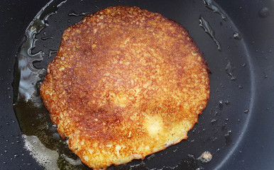 Delicious Bramborak on a non-stick pan. Top view. Flat lay. Cooking process. Pancakes recipe. Big potato pancake.