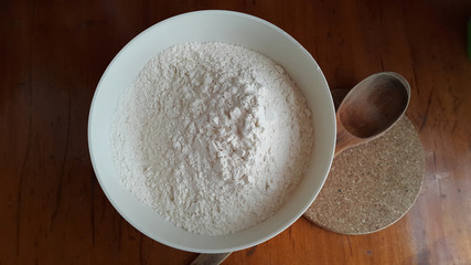 Flour in a white bowl with a wooden spoon. Cooking process. Pancakes recipe. 