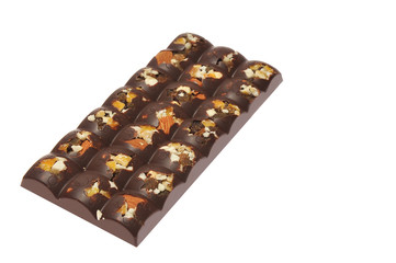 Bar of milk chocolate with raisins and dried apricots on a background of cinnamon sticks close-up