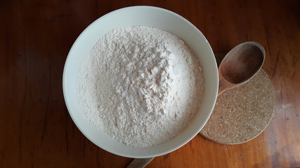 Flour,tremors, salt, sugar, water in a white bowl on a wooden table. Cooking process. Pancakes recipe. 