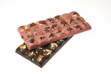 Two bars of milk and pink chocolate with raisins and dried apricots close-up