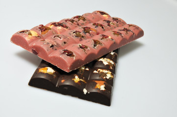 Two bars of milk and pink chocolate with raisins and dried apricots close-up
