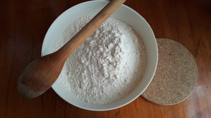 Flour,tremors, salt, sugar, water in a white bowl on a wooden table. Cooking process. Pancakes recipe.	
